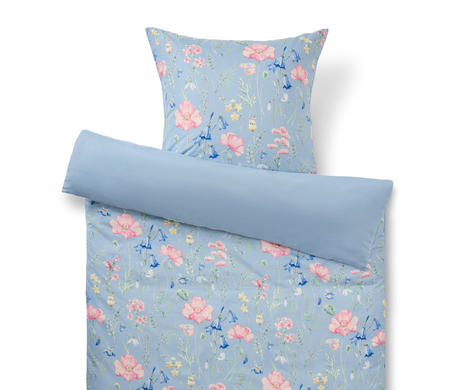 Hellblaue Bettwäsche mit Blumenmuster, bestehend aus Kissenbezug, Deckenbezug und Nackenrolle.