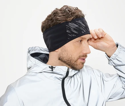 Mann richtet schwarzes Stirnband mit weißem Muster. Er trägt eine silberne Jacke mit Kapuze.