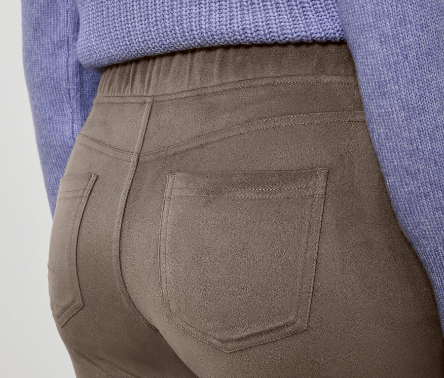 Detailaufnahme einer braunen Hose und eines lila Pullovers.