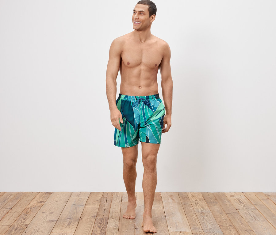 Mann trägt Badeshorts und geht.