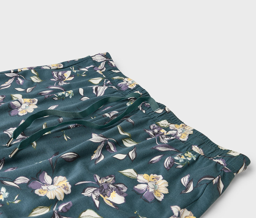 Nahaufnahme einer dunkelgrünen Hose mit Blumenmuster und einem grünen Kordelzug.