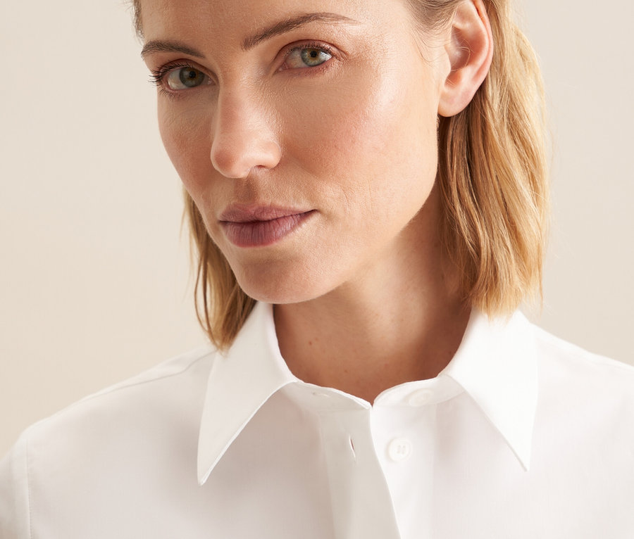 Porträt einer blonden Frau in einer weißen Seidensticker Kurzarm-Bluse.