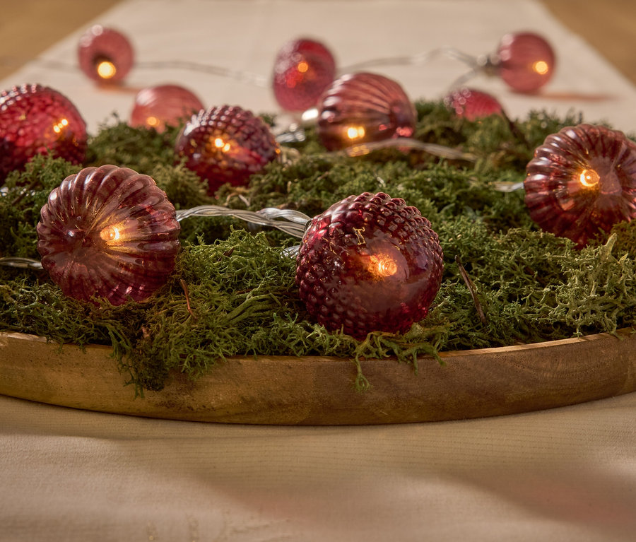 Dekorative rote Lichter auf Moos in einer Holzschale.