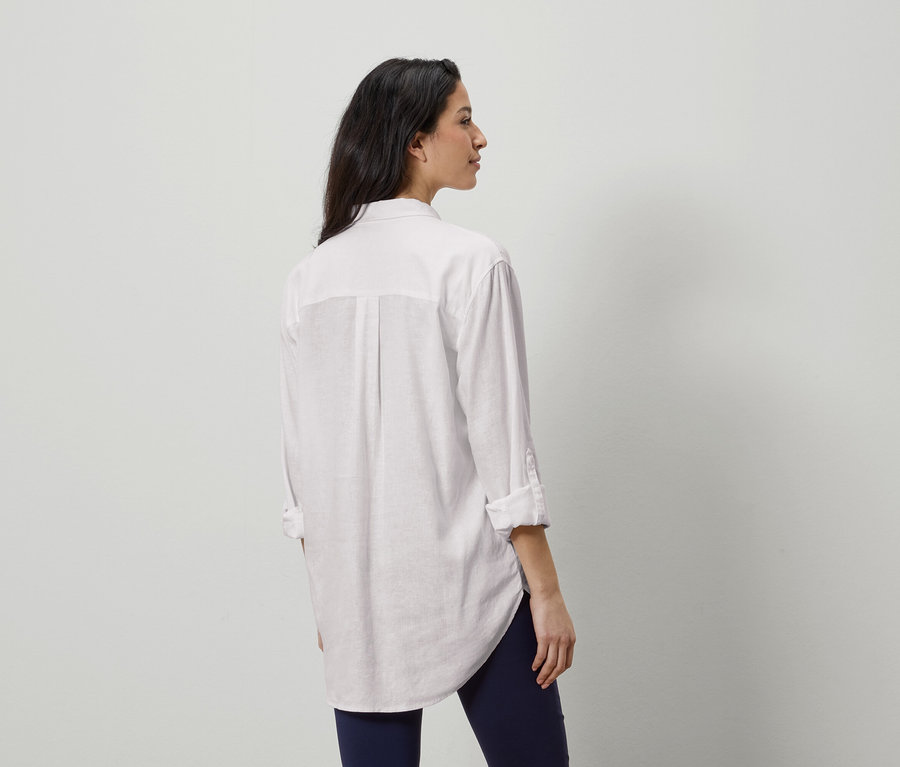 Frau von hinten in einem weißen Hemd und blauen Leggings.