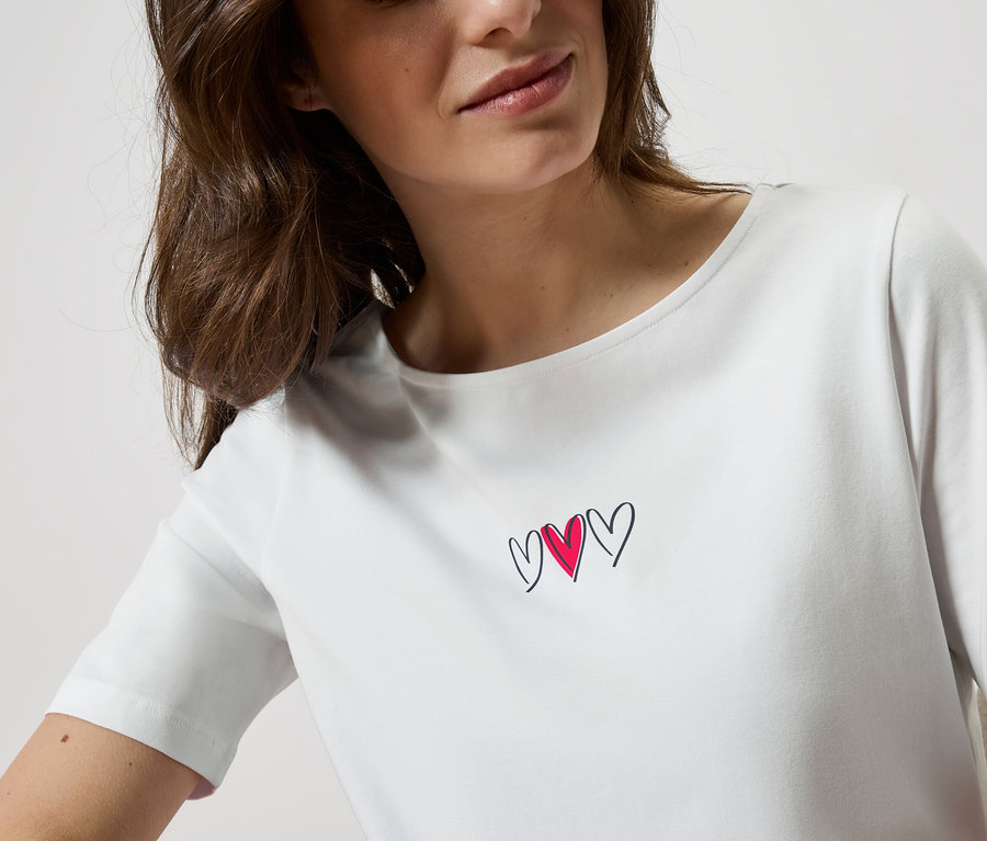 Frau trägt ein weißes T-Shirt mit drei Herzen.