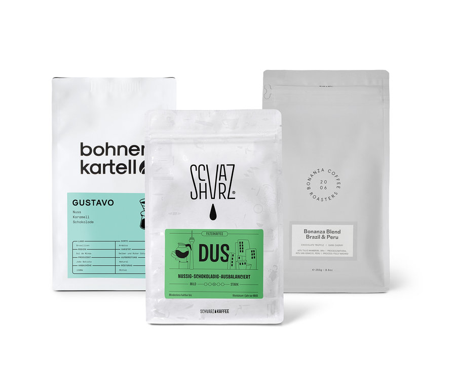 Drei Packungen Filterkaffee Probierset "Dreierpack schokoladig" mit ganzen Bohnen stehen auf einer weißen Oberfläche.