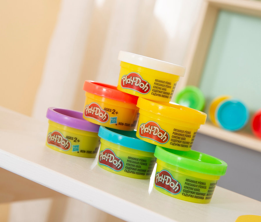 Gestapelte, bunte Play-Doh-Dosen des roba x Play-Doh Sitzgruppen-Sets auf einem weißen Regal.