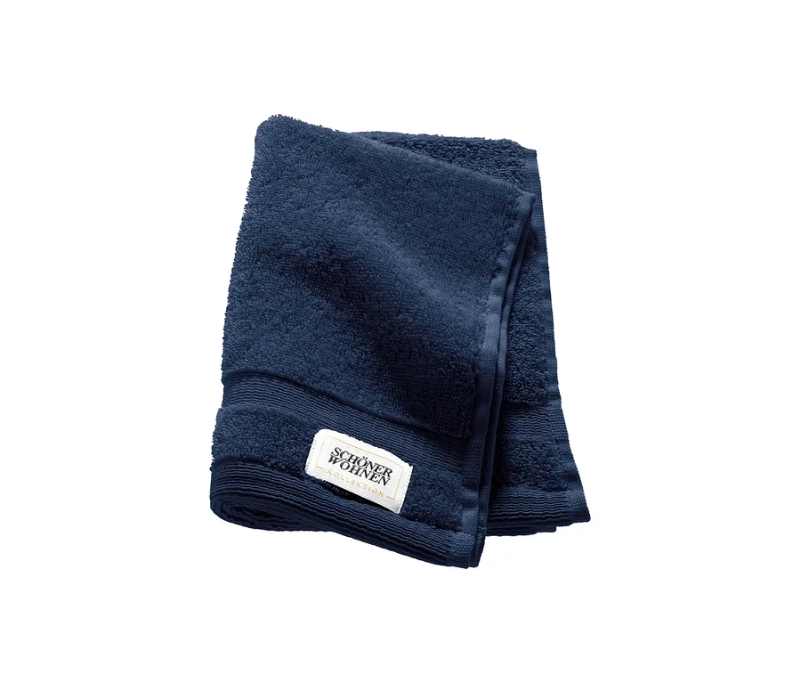 Ein blaues, gefaltetes Gästehandtuch der SCHÖNER WOHNEN-Kollektion mit sichtbarem Markenetikett.