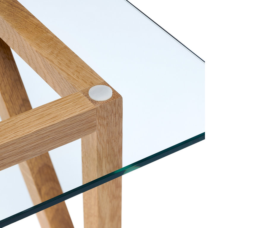 Detail einer Ecke eines Couchtischs mit Holzrahmen und Glasplatte.