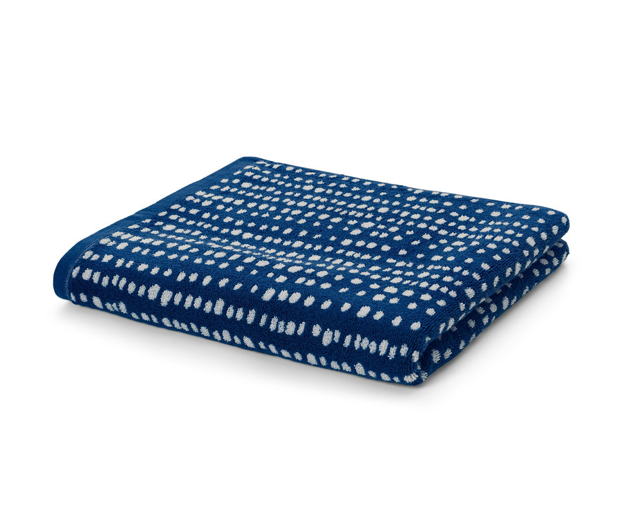 Zusammengelegtes Jacquard-Badetuch in Blau mit weißen Tupfen.