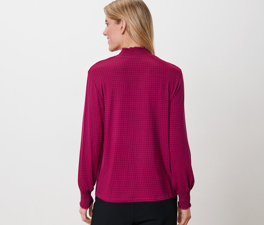 Frau trägt ein bedrucktes Blusenshirt mit Stehkragen.