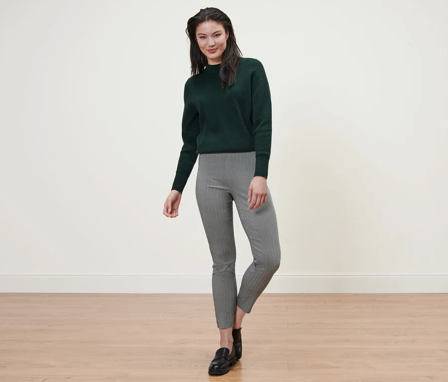 Frau posiert in einem Pullover und einer bedruckten Stretchhose.