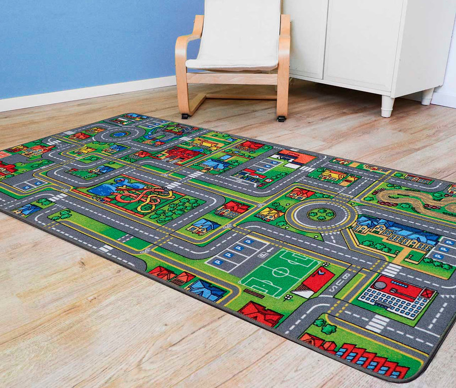 Ein Spielteppich STREETS, ca. 95 x 133 cm, liegt auf einem Holzboden. Im Hintergrund sind ein weißer Schrank und ein Stuhl zu sehen.