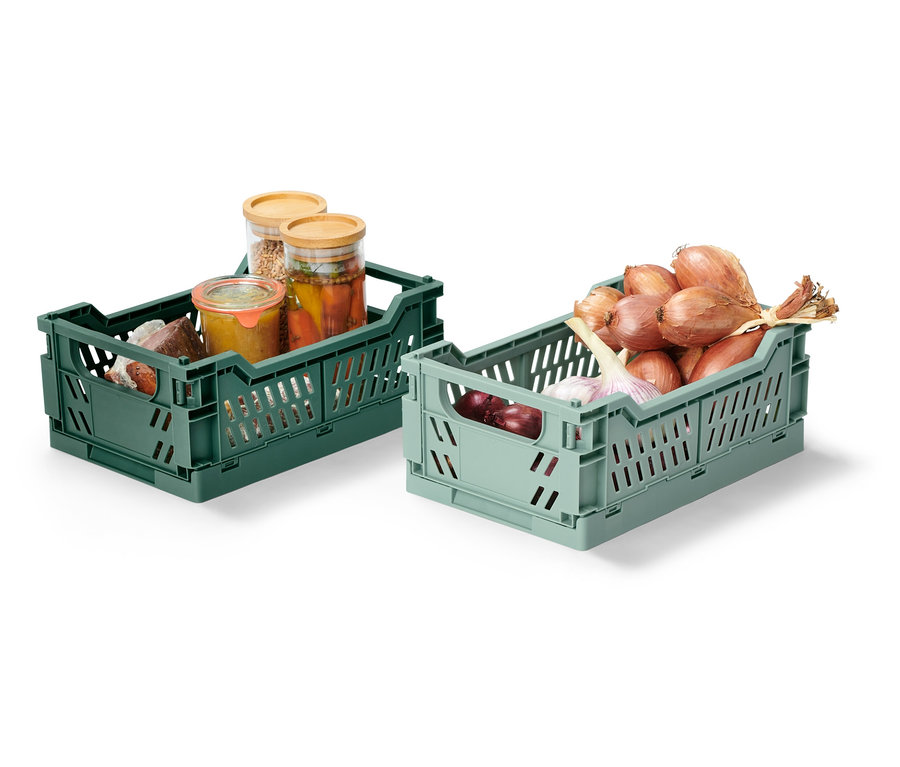 Zwei klappbare Ordnungskisten, eine grüne mit eingelegten Gläsern, eine hellgrüne mit Zwiebeln und Knoblauch.