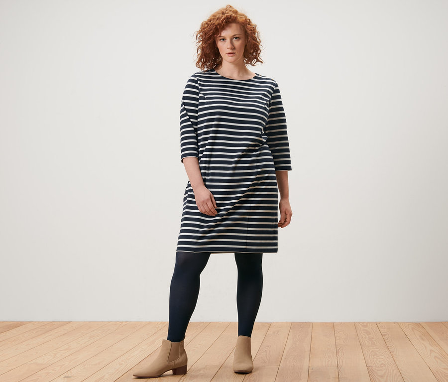 Frau steht in einem gestreiften Sweatkleid und 2 Paar Feinstrumpfhosen.