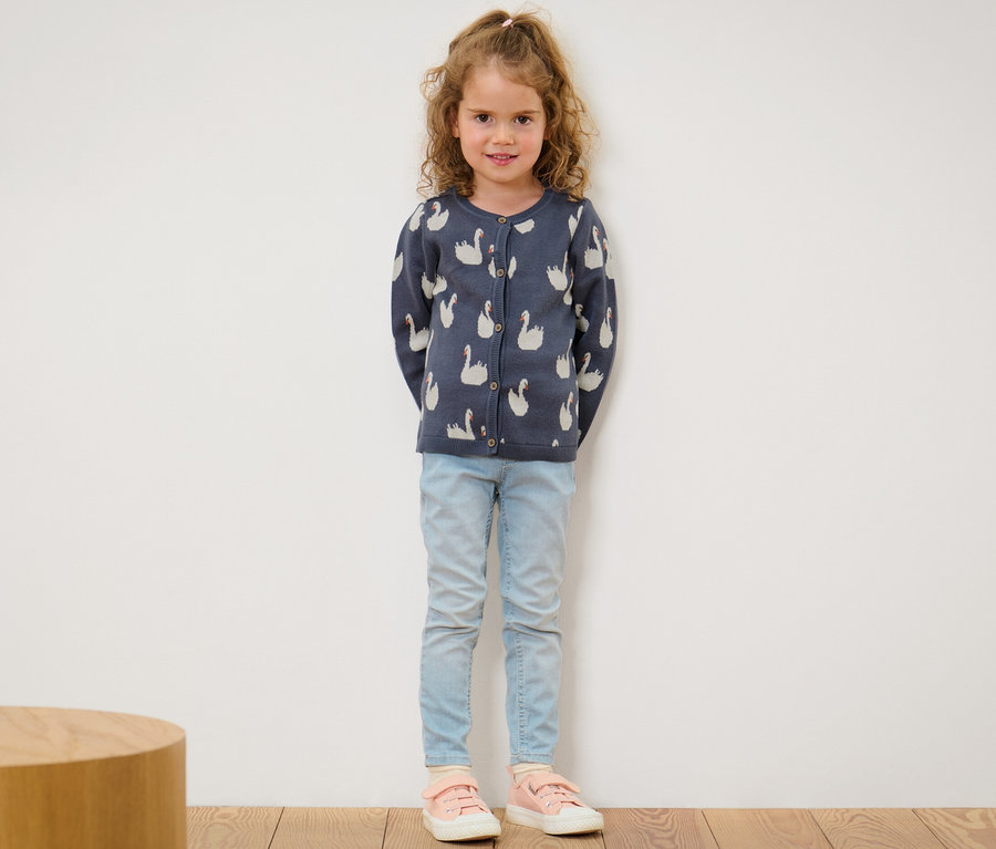 Mädchen trägt eine Kinder-Strickjacke mit Schwanenmuster.
