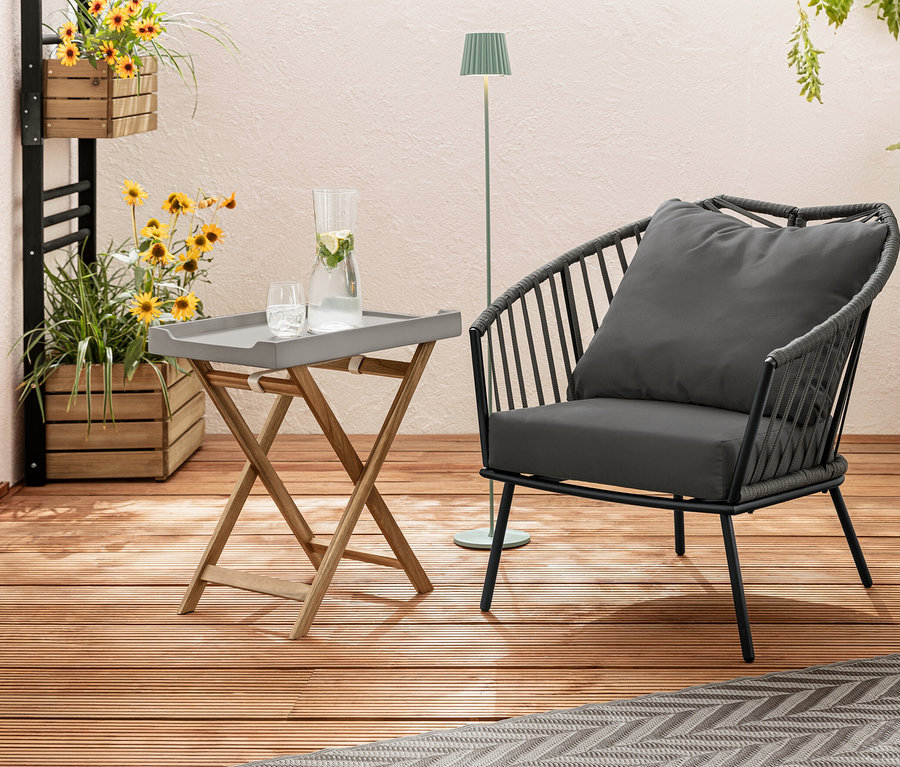 Auf einer Holzterrasse stehen ein Relax-Sessel mit Textilgeflecht, ein Outdoor-Teppich, ca. 165 x 115 cm, beige-hellgrau, und eine Pflanzwand »Elin« mit Blumen. Im Hintergrund ist eine LED-Akku-Outdoor-Stehleuchte, salbei.