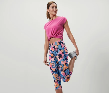 Frau dehnt Bein in 3/4-Sporttight mit Blumenmuster.
