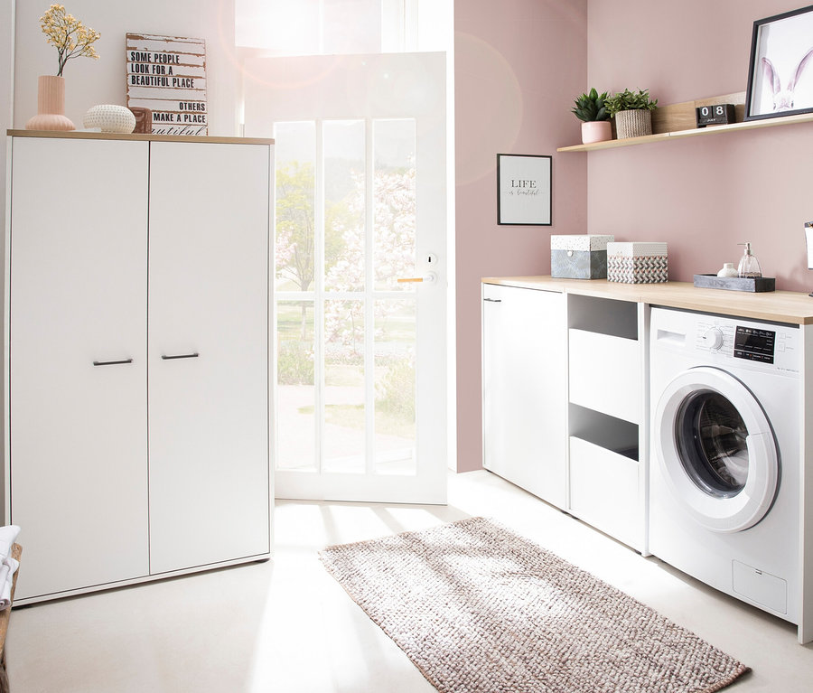 Einrichtung eines Waschraums mit einer weißen Waschmaschine, Schränken und einer offenen Tür. Zu sehen ist ein Mehrzweckschrank »Solea« in matt weiß.