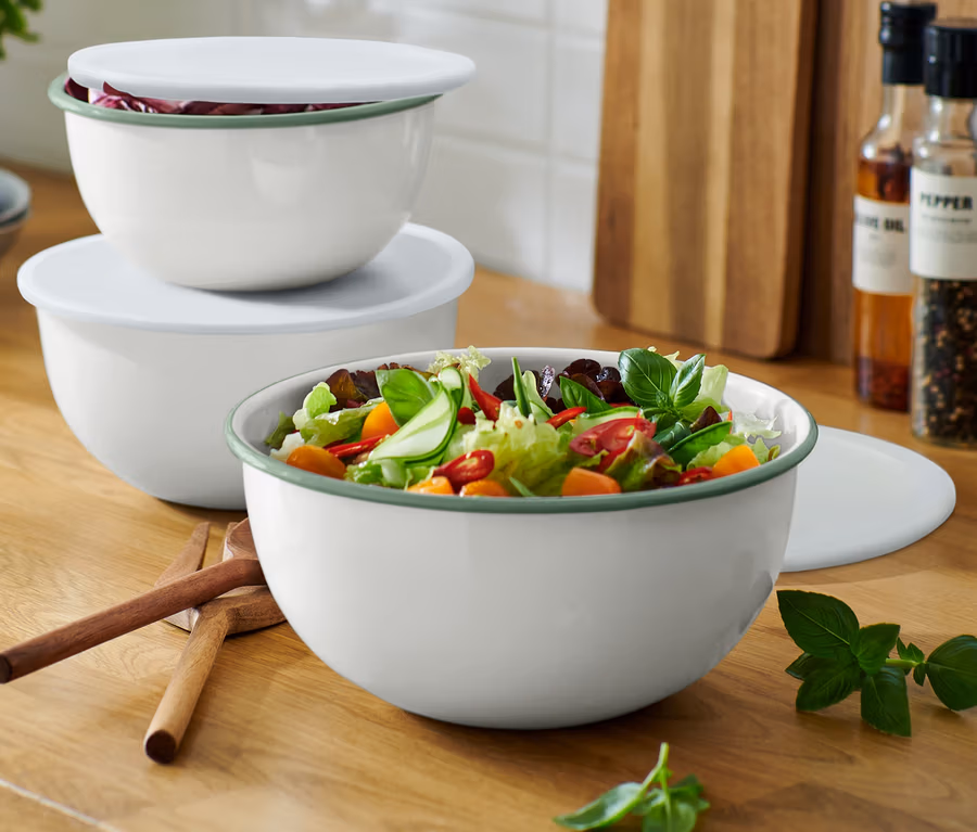 Drei Emaille-Servier-und-Zubereitungsschüsseln mit Deckeln stehen auf einer Küchentheke, die grösste Schüssel ist mit Salat gefüllt.