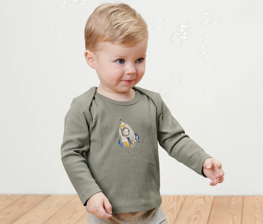 Kleiner Junge trägt ein geripptes Shirt mit einem Raumschiff-Motiv aus dem Set 2 Baby-Rippshirts, Outerspace.