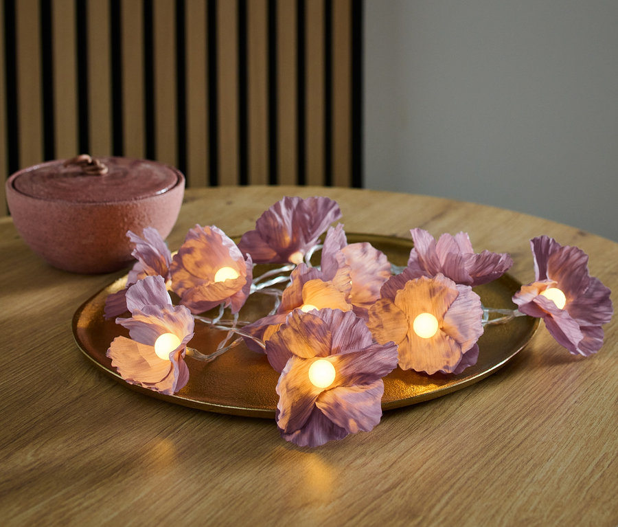 LED-Lichterkette, Blumen, auf goldenem Teller auf Holztisch.