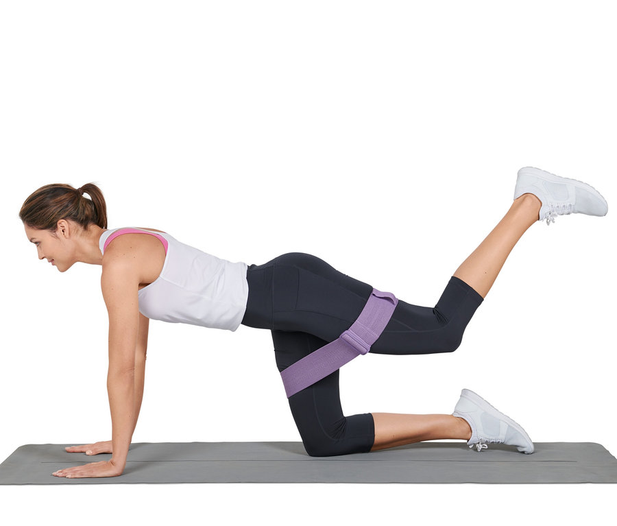 Frau macht Übungen auf einer Matte mit einem verstellbaren Fitnessband.