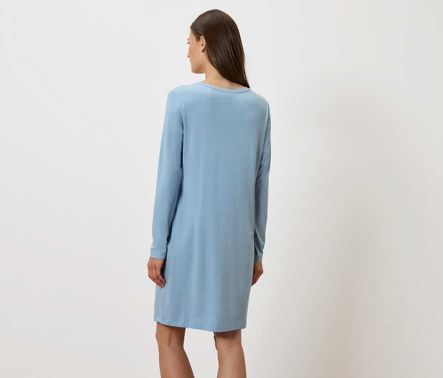 Frau mit dem Rücken zur Kamera trägt ein blaues, langärmliges Kleid.