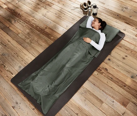 Frau liegt in Seiden-Schlafsack-Inlay auf einer Matte.