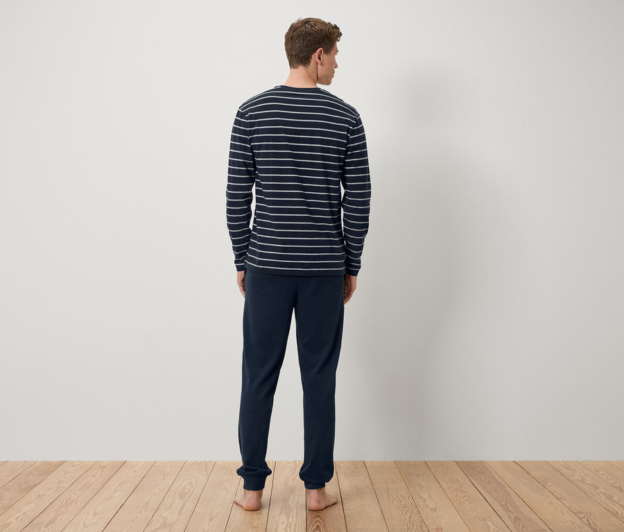 Ein Mann mit dem Rücken zur Kamera trägt ein dunkelblaues, gestreiftes Langarmshirt und eine dunkelblaue Trainingshose.