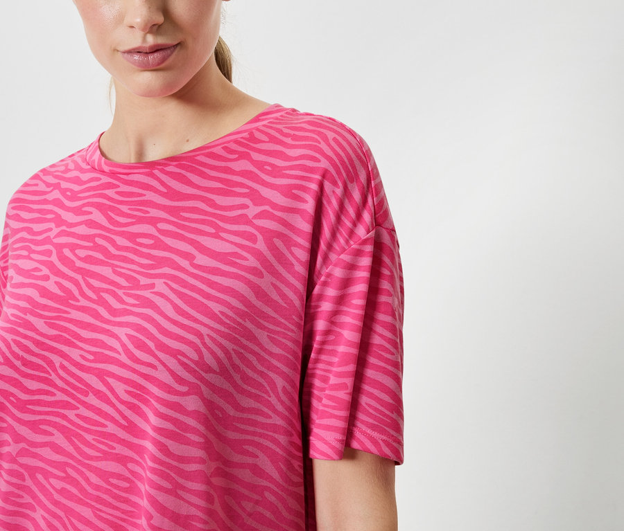 Frau trägt ein pinkes T-Shirt mit Tiermuster.
