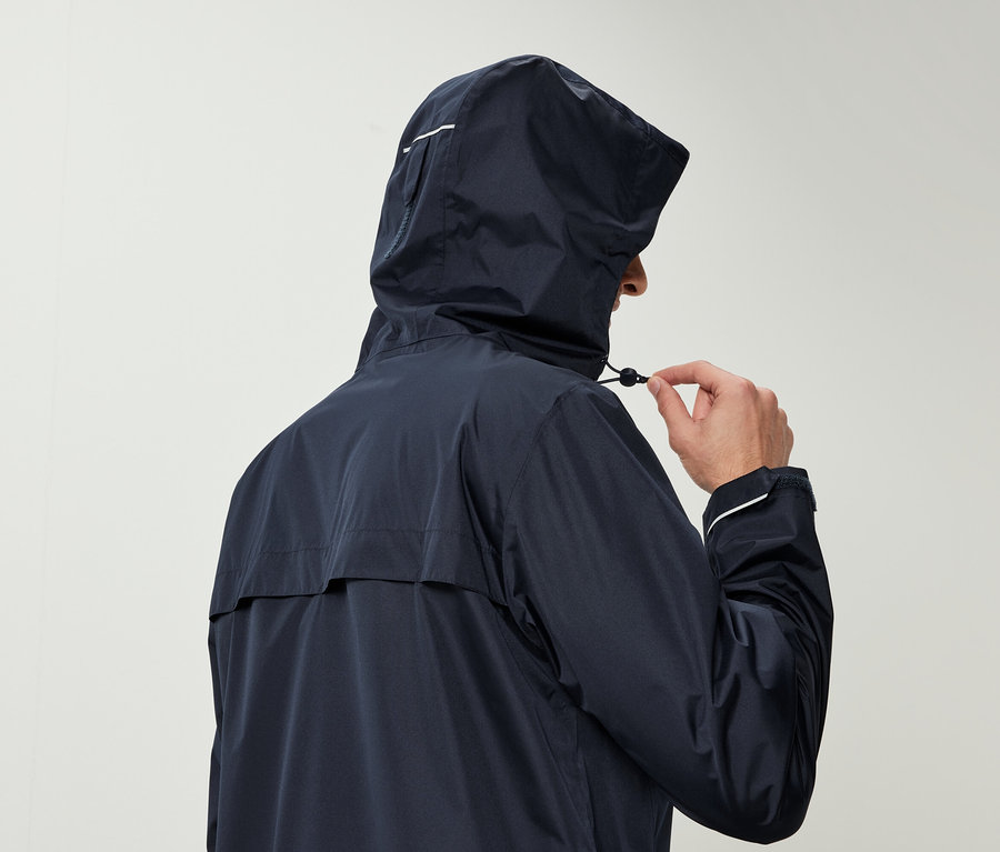 Mann in dunkelblauer Regenjacke mit Kapuze zieht an der Kordel der Kapuze.