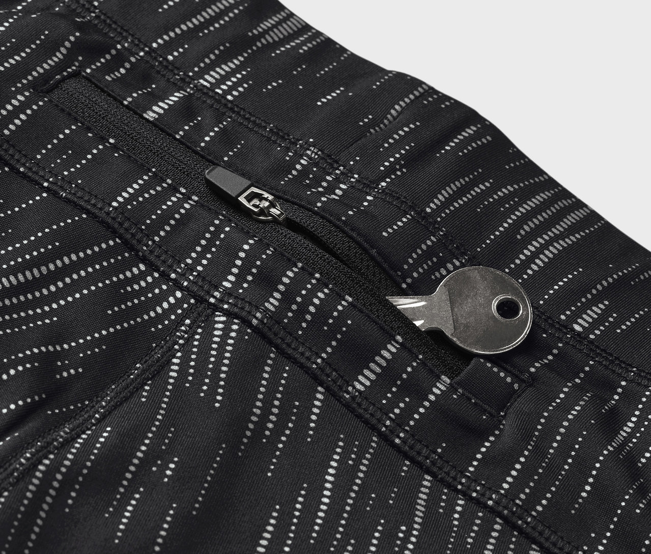 Detailaufnahme von schwarzen Leggings mit Muster und einem Schlüssel in der Reißverschlusstasche.
