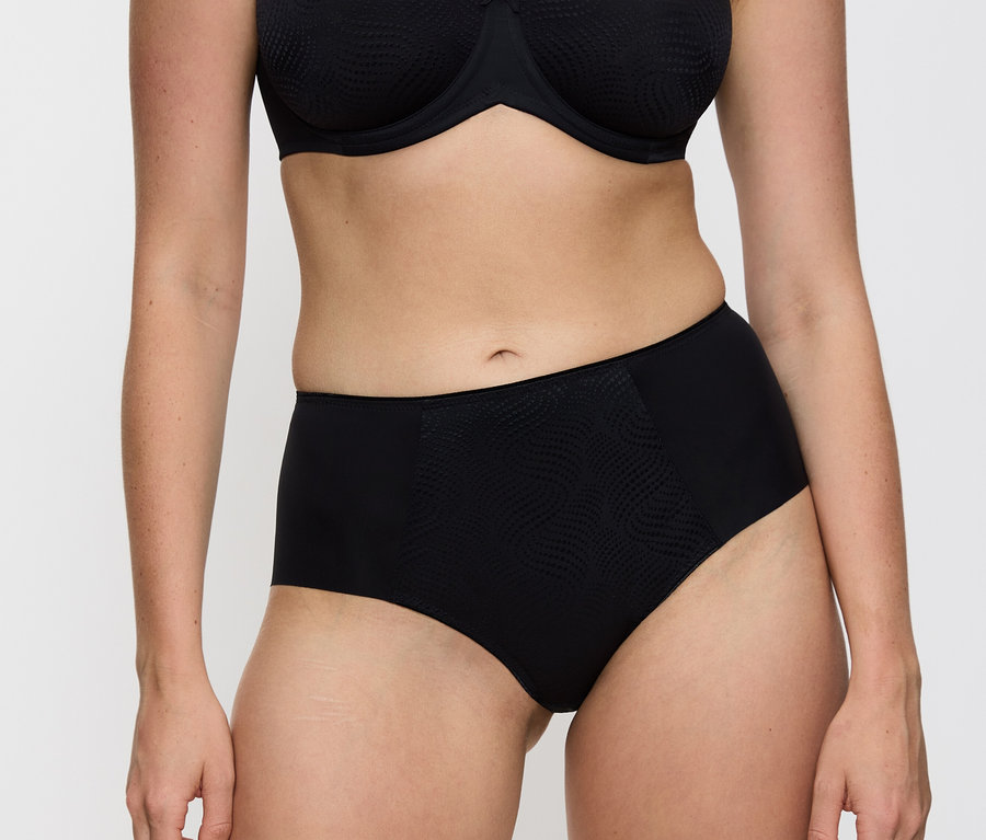 Frau trägt schwarzen BH und schwarze Triumph Essential »Minimizer Hipster X« Unterhose.