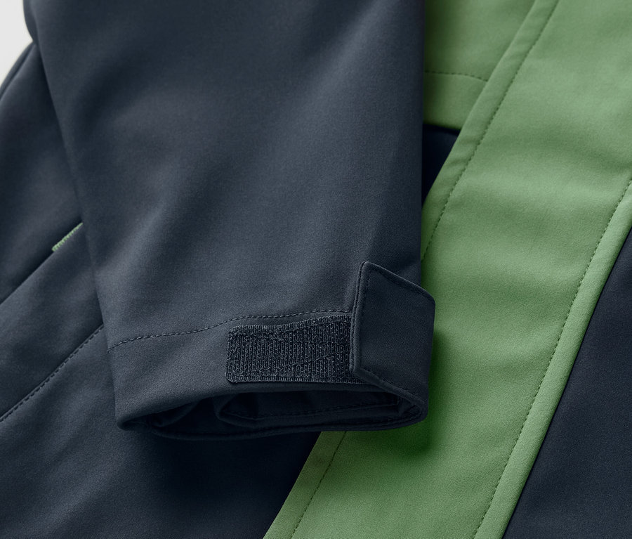 Detailansicht einer Kinder-Softshelljacke in Blau und Grün mit Klettverschluss am Ärmel.