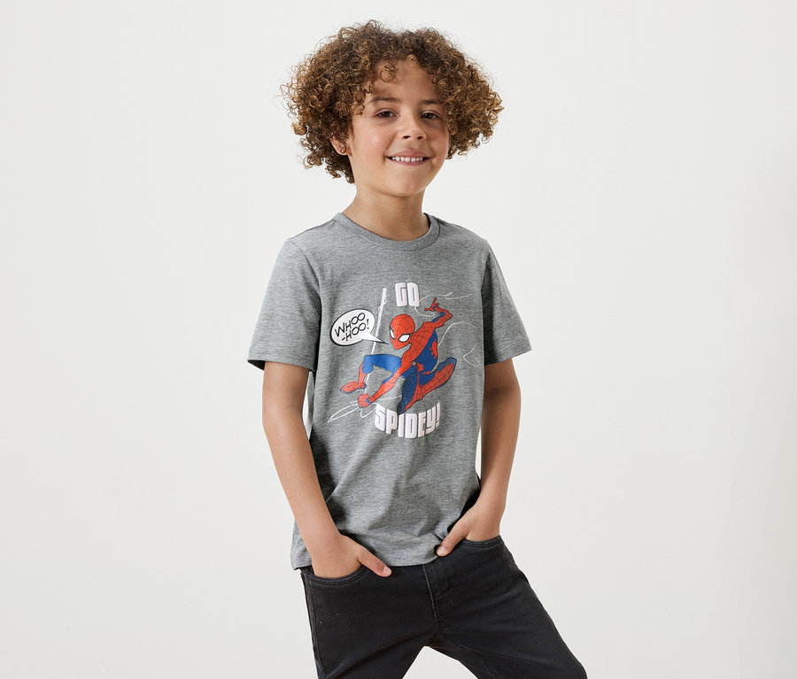 Ein Junge mit lockigem Haar trägt ein graues T-Shirt mit Spiderman-Aufdruck.
