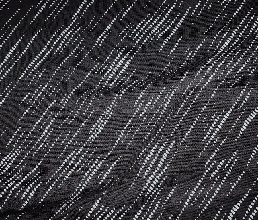 Detailaufnahme eines schwarzen Stoffes mit diagonalen, gepunkteten, weißen Linien.