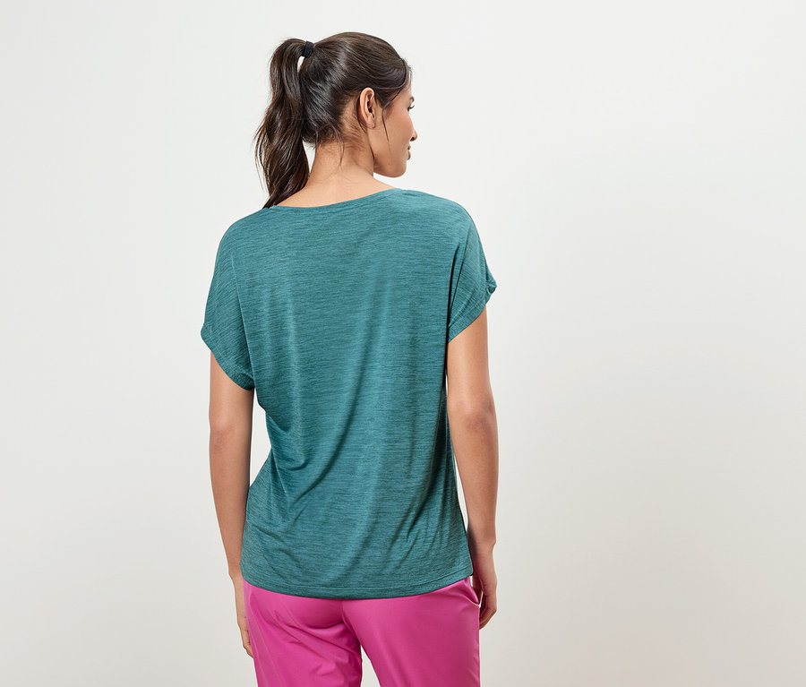 Rückansicht einer Frau mit Pferdeschwanz, die ein blaugrünes T-Shirt und eine pinkfarbene Hose trägt.