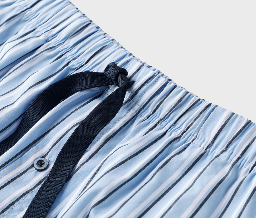 Detailaufnahme von blau-weiß gestreiften Pyjamahose mit dunkelblauem Kordelzug.