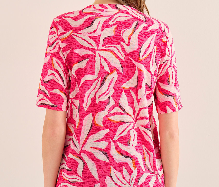 Frau von hinten in einem rosa CECIL Kurzarmshirt mit weißem Blattmuster und blauen Jeans.