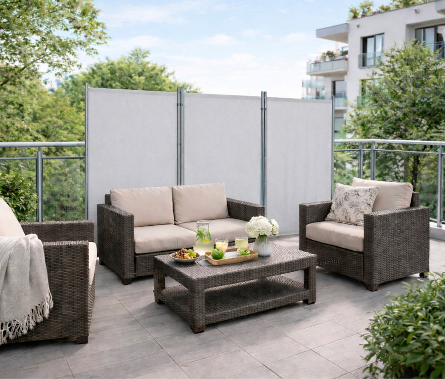 Auf einer Terrasse steht eine hellgraue, 3-teilige Leco Stellwand hinter einem Sofa, Sessel und Tisch.