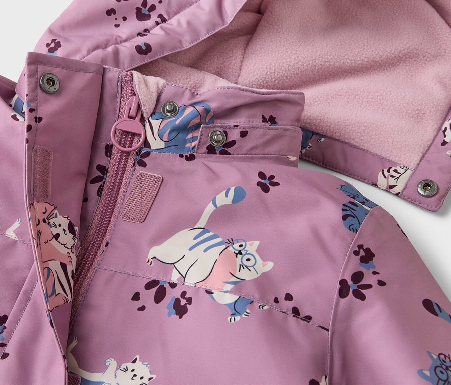 Nahaufnahme einer lila Jacke mit Katzen- und Blumenmuster, Reißverschluss und Kapuze mit rosa Fleecefutter.
