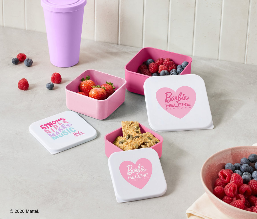 Auf einer Küchentheke stehen rosa Behälter mit Erdbeeren, Himbeeren, Blaubeeren und Keksen, zusammen mit einem lila Becher und einer Schüssel mit Beeren.