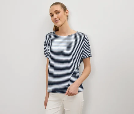 Frau mit Pferdeschwanz trägt ein blau-weiß gestreiftes T-Shirt und weiße Hose.