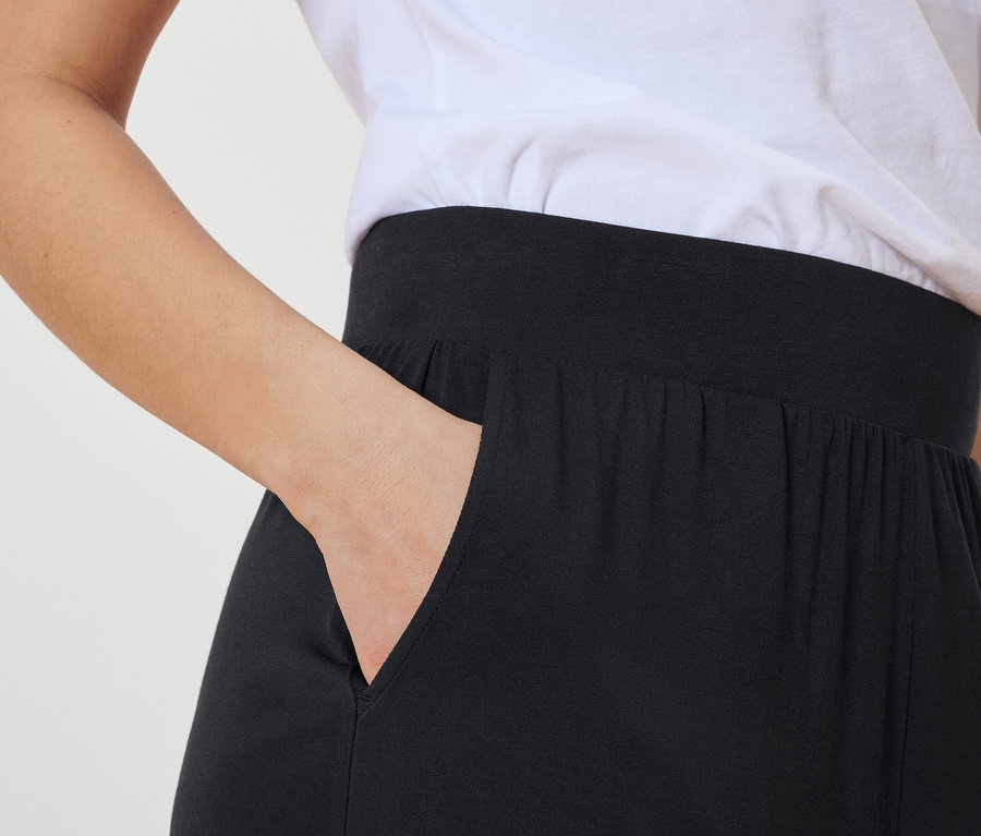 Frau steckt Hand in die Tasche einer schwarzen Hose