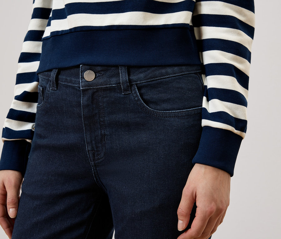 Eine Person trägt eine dunkelblaue Jeans und ein gestreiftes Oberteil mit blauen und weißen Streifen.