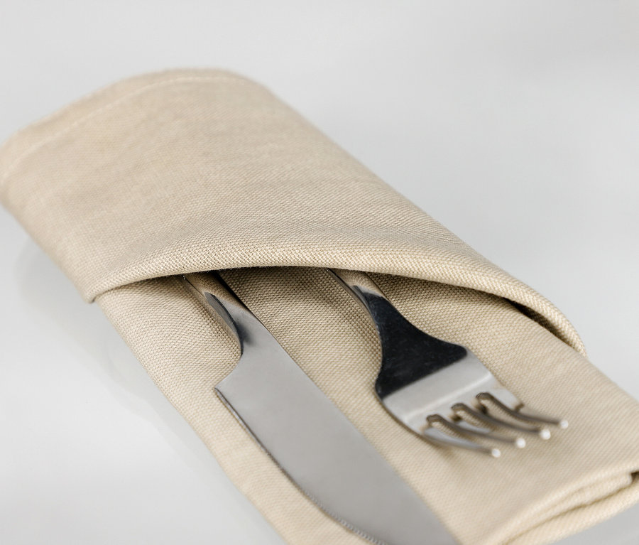 Eine sandfarbene Serviette der SCHÖNER WOHNEN-Kollektion ist um ein silbernes Besteckset aus Gabel und Messer gefaltet.