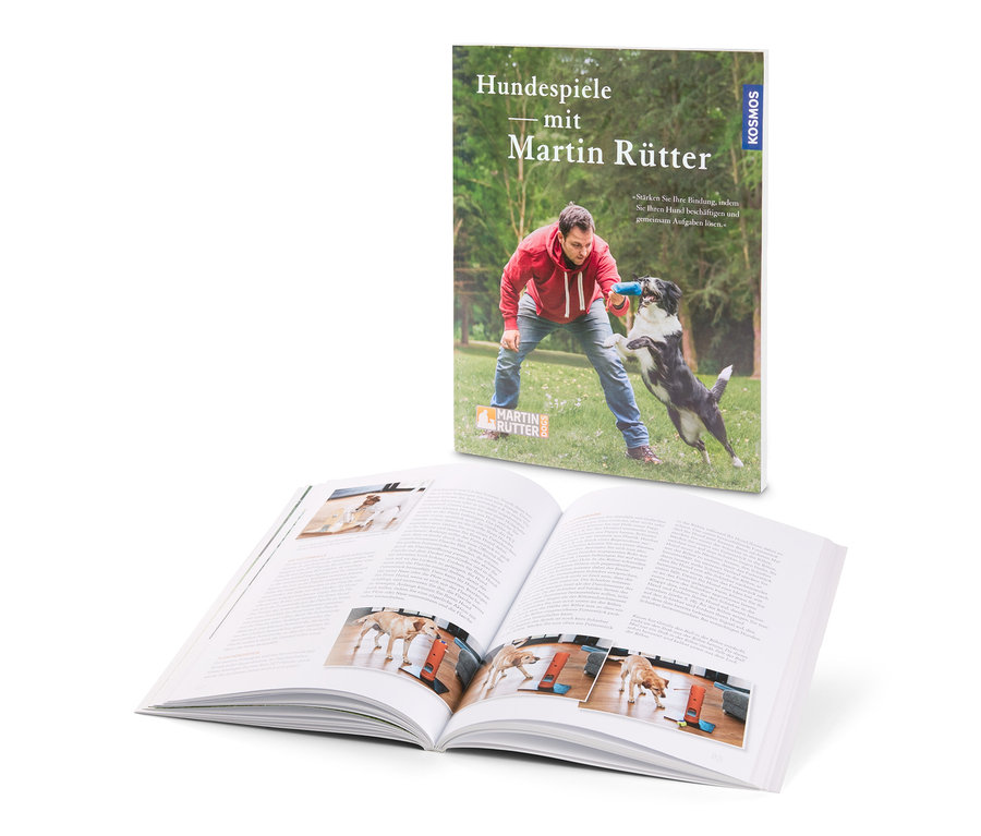 Buch "Hundespiele mit Martin Rütter" mit Mann, der mit Hund spielt und offenem Buch mit Fotos von Hunden.