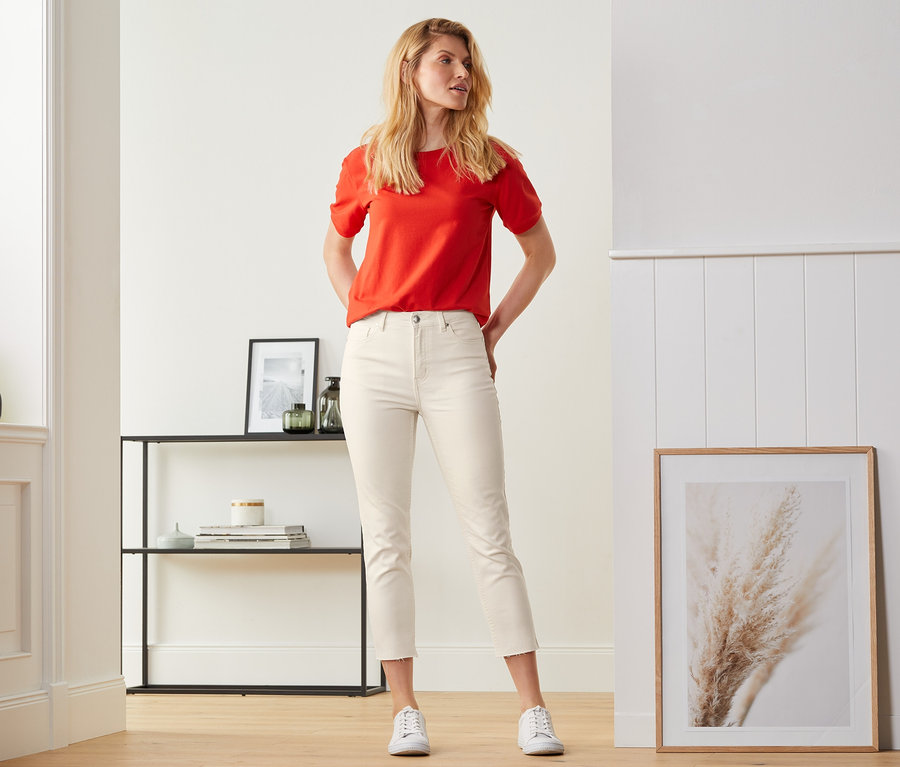 Eine Frau posiert in Straightfit-Jeans und einem roten Oberteil.