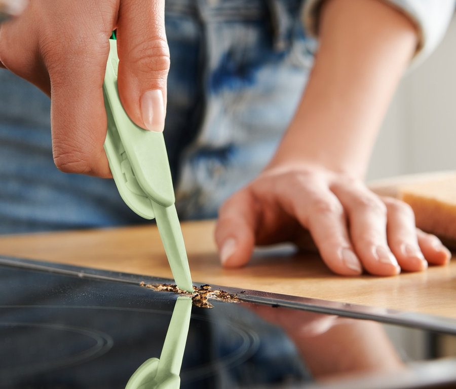 Frau reinigt Glaskeramikkochfeld mit 3-in-1-Multifunktionsbürste.